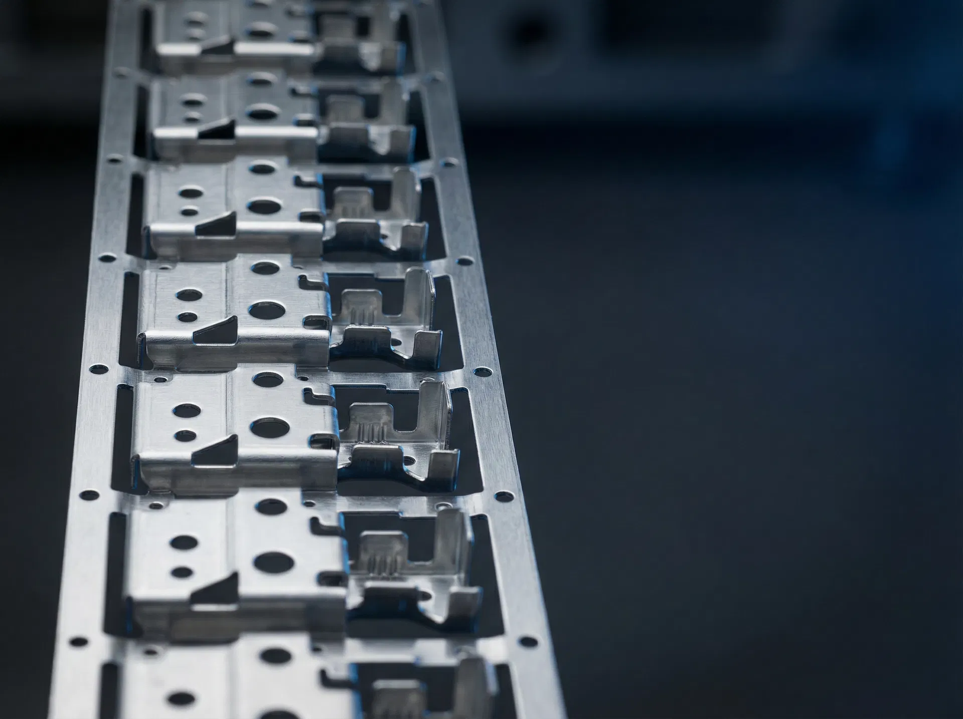 SS304 progressive die stamping strip showing multi-stage complex bracket forms with precision punched holes and clean sheared edges — Hengya Stamping